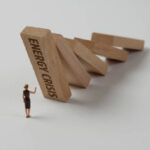 Businesswoman figurine trying to stop the domino effect. Energy Crisis concept.