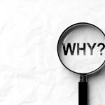 Why with question mark inside magnifying glass on paper background.