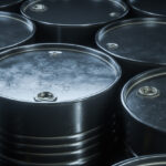 Group of black barrels with oil closeup.