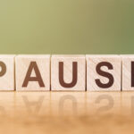 Wooden Blocks with the text: Pause on a green-brown background
