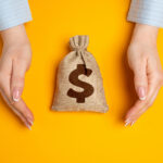 Hands in a gesture of protection of money bag. Concept of capital protection and guarantee of safety of investments and deposits. Financial security. Secure savings