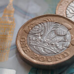 British one pound coin placed on top of polymer 5 Pound banknote with visible Big Ben symbol.