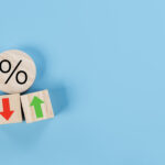 Percentage icon on wooden cube block and up and down arrow symbol on flipping white dice on blue background