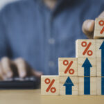 Businessman putting red percentage sign with increasing up arrow for financial interest rate and business investment growth from dividend concept.