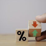 Hand flipping wooden cube block to change between up and down with percentage sign symbol for increase and decrease financial interest rate and business investment growth from dividend concept.