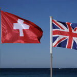 National flags of Switzerland and the United Kingdom next to the sea