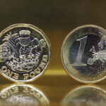 1 pound and 1 euro coin over metal background