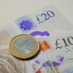 One euro coin resting on british pound banknotes